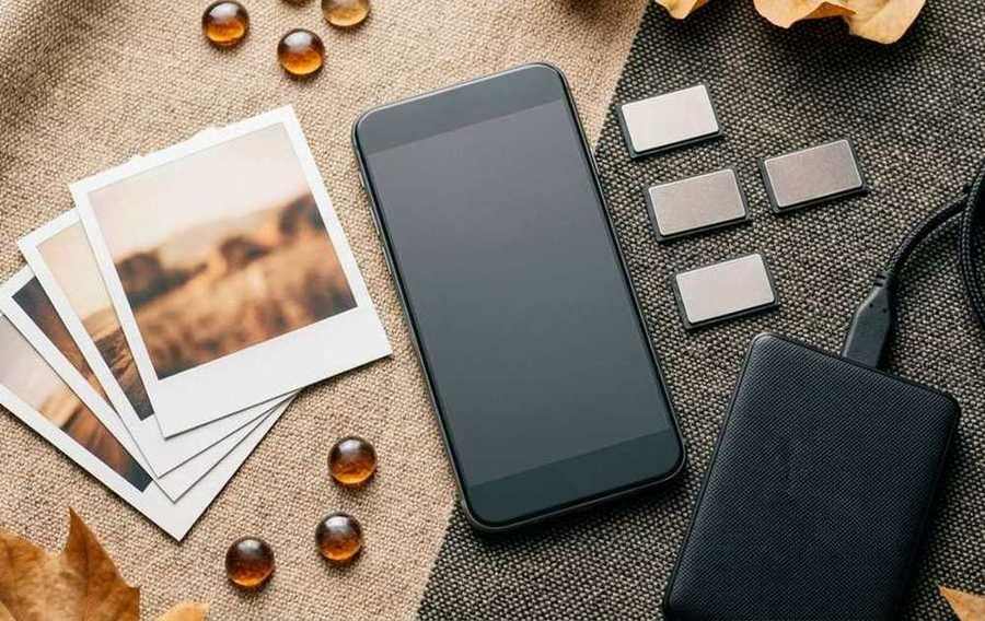 Smartphone beside photos, memory cards, and a portable drive